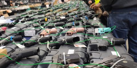 Customers examine handguns at a 2023 gun show