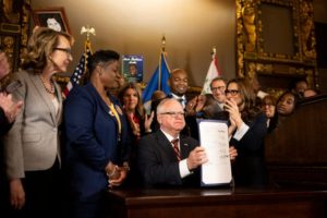 Minnesota Gov. Tim Walz holds up a just-signed gun control bill Friday, May 19, 2023, at the Minnesota State Capitol in St. Paul, Minn. Walz signed a sweeping public safety bill into law, including two gun measures: universal background checks and a red flag-style provision allowing law enforcement to intervene when someone is at high risk of injuring themselves or others with a firearm.