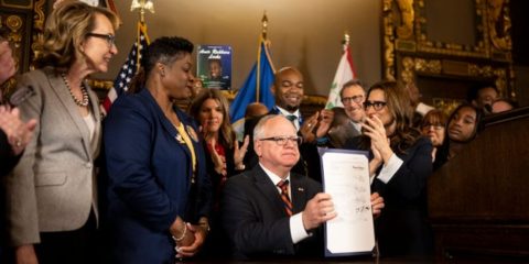 Minnesota Gov. Tim Walz holds up a just-signed gun control bill Friday, May 19, 2023, at the Minnesota State Capitol in St. Paul, Minn. Walz signed a sweeping public safety bill into law, including two gun measures: universal background checks and a red flag-style provision allowing law enforcement to intervene when someone is at high risk of injuring themselves or others with a firearm.